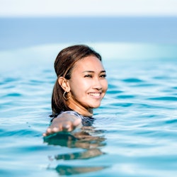 front view of Asian young woman swim in pool looking boats at  a sea