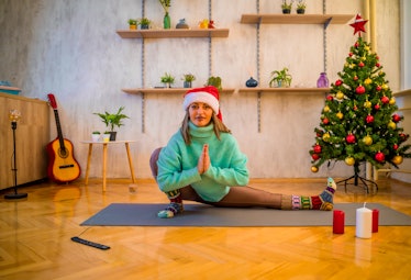 Young woman doing yoga exercises on parquet floor in the Christmas home interior