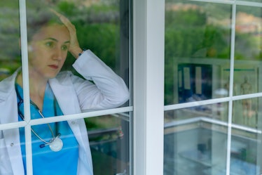 Upset female nurse standing in hospital window