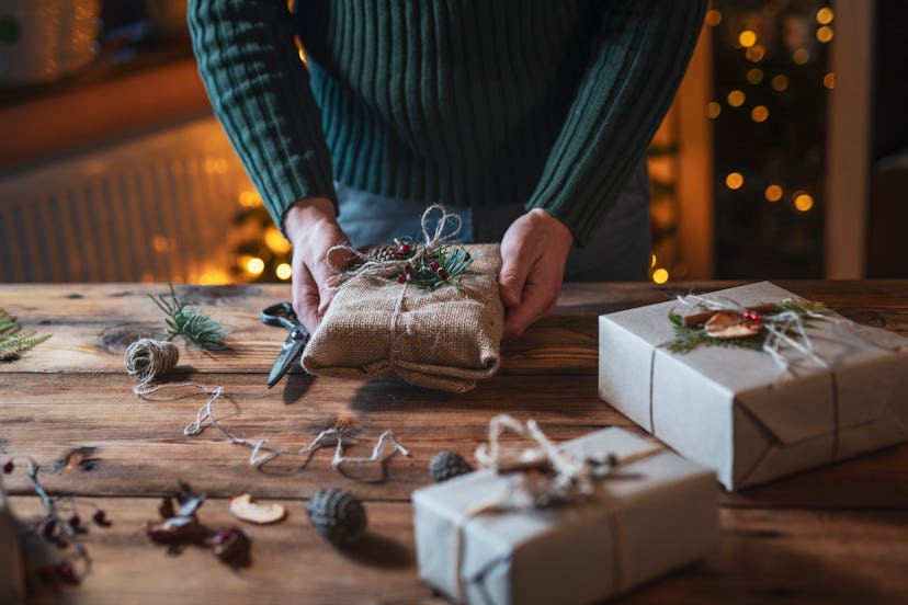 Close up of unrecognizable male hands wrapping Christmas gifts with natural materials.