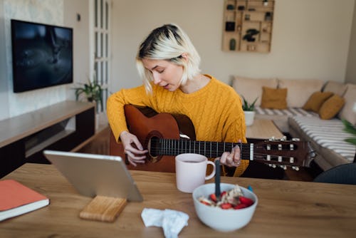 A woman plays the guitar. Here's your daily horoscope for december 15 2021.