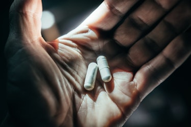 Hands holding pills in dramatic light.