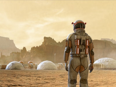Rear view of an astronaut on Mars looking at the base camp settlement built near a rocky mountain ra...