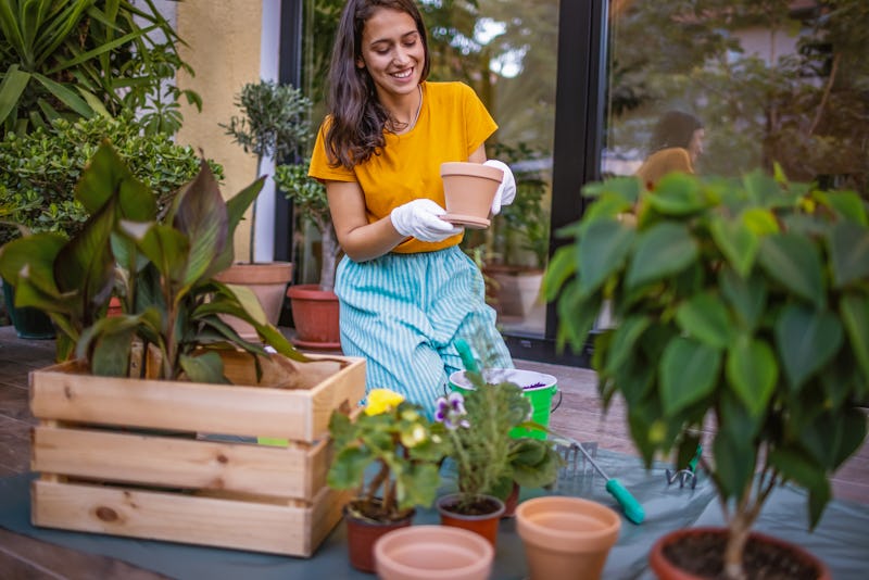 Photo of a young woman taking care of her plants at balcony