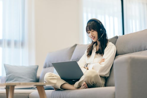 Young Asia businesswoman using laptop talk to colleagues about plan in video call while smart workin...