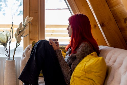 Beautiful young woman reading a book. She sitting on the sofa in the living room.