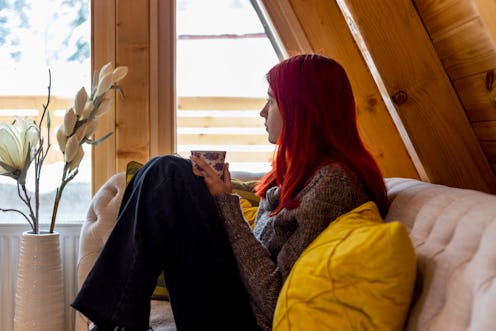 Beautiful young woman reading a book. She  sitting on the sofa in the living room.