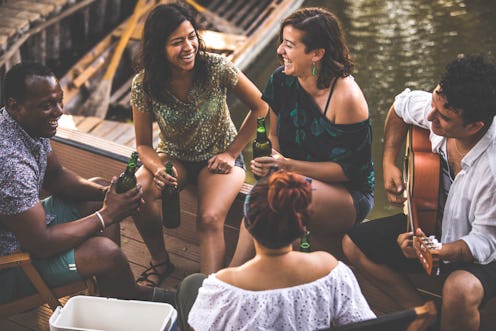 High angle view of small group of happy young people, friends, having fun chatting, playing guitar, ...