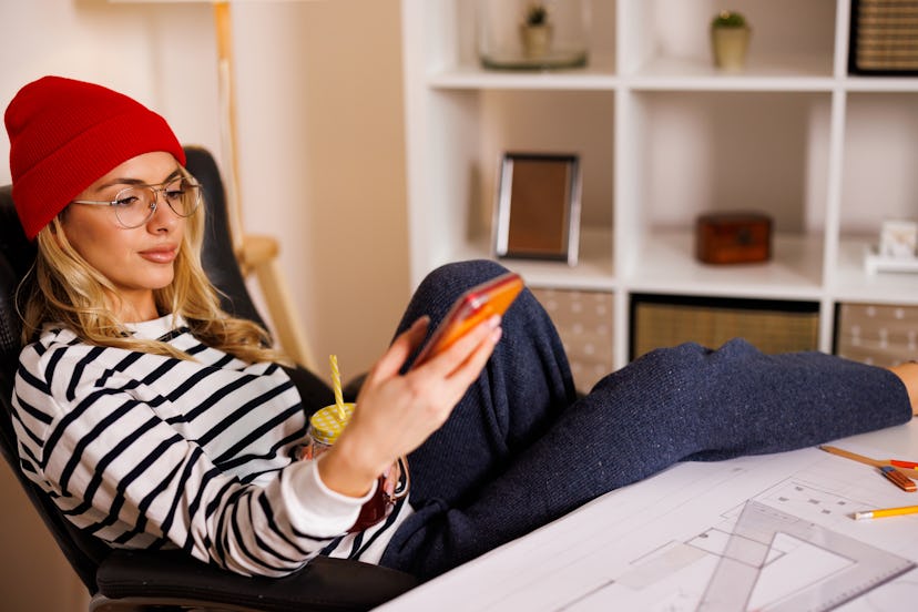 Young woman in her modern home office looking at photo dump captions on her phone