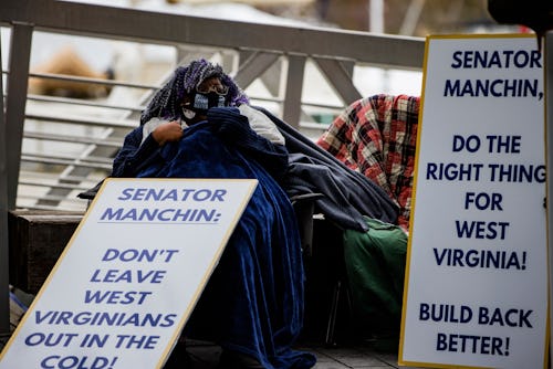 Activists with the Center for Popular Democracy hold signs near the entrance where Senator Joe Manch...
