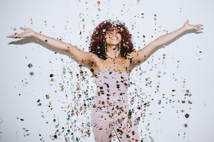 A young woman raises her hands in celebration listening to New Year's song lyrics.