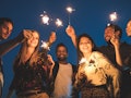 Group of friends enjoying rooftop party with sparklers for new years eve, for which they'll need New...