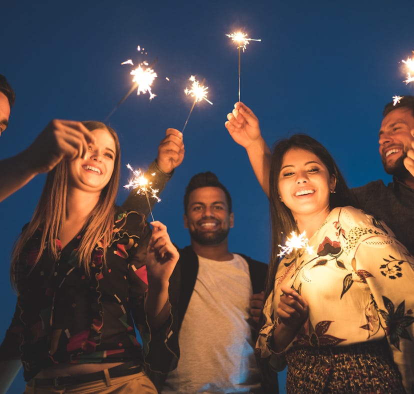 Group of friends enjoying rooftop party with sparklers for new years eve, for which they'll need New...