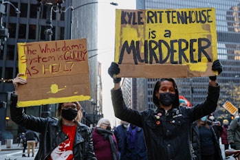 Demonstrators hold signs as they march in protest of the not guilty verdict in Kyle Rittenhouse's mu...