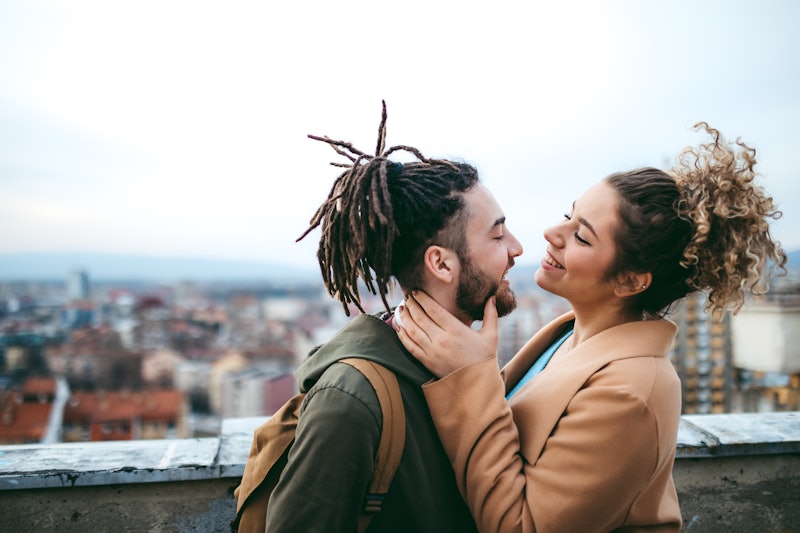A young couple lovingly looking at each other on the rooftop of a building.