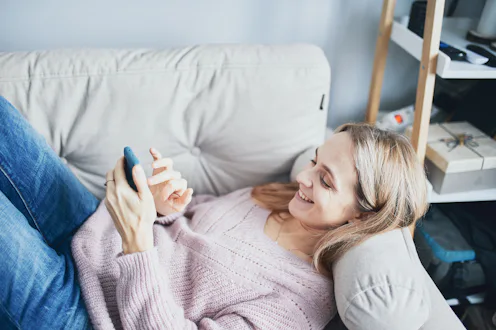 Beautiful blonde girl with a mobile phone at home.