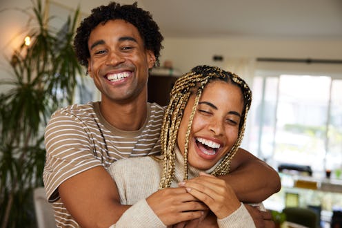 Portrait of a carefree young couple standing in each other's arms at home and laughing