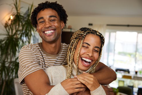 Portrait of a carefree young couple standing in each other's arms at home and laughing