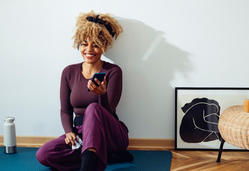 A woman on a yoga mat laughs at Instagram Reels. What's the difference between Instagram Reels and T...