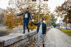 Beautiful young couple having fun on the city quay, wearing leather jackets, she has a bandana on he...