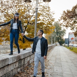 Beautiful young couple having fun on the city quay, wearing leather jackets, she has a bandana on he...