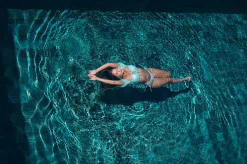 Attractive young woman is floating on water in the pool.