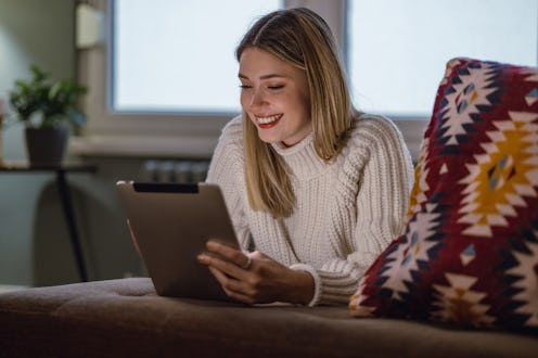 A beautiful woman with blond hair is using a digital tablet at home at night