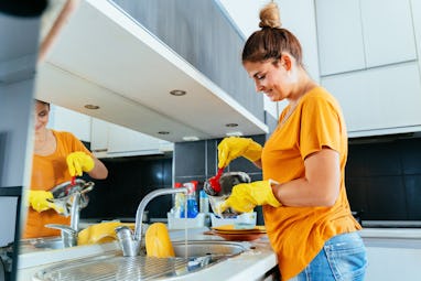 Beautiful young woman washing dishes
