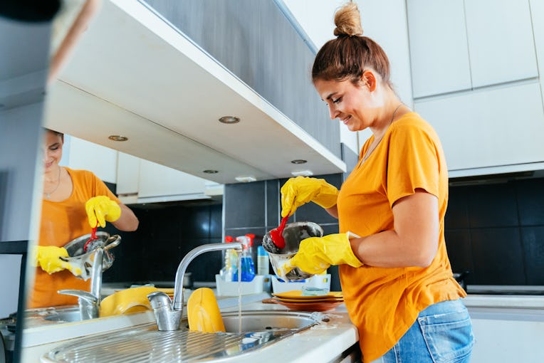Beautiful young woman washing dishes