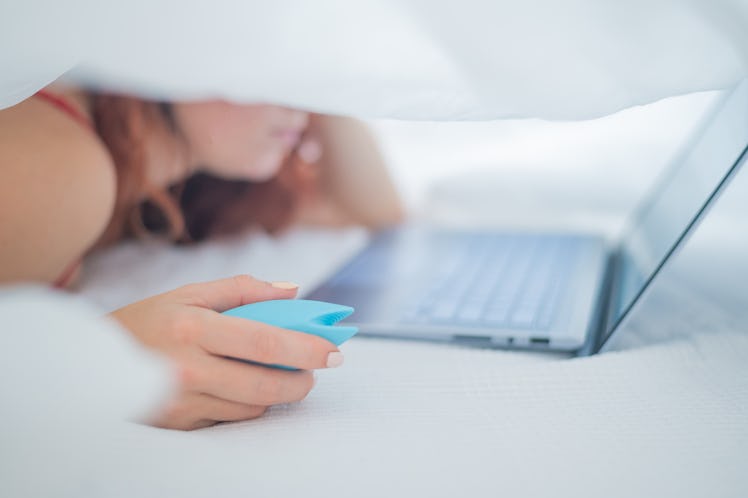 A woman holds a vibrator while watching porn after discussing it with her friends.