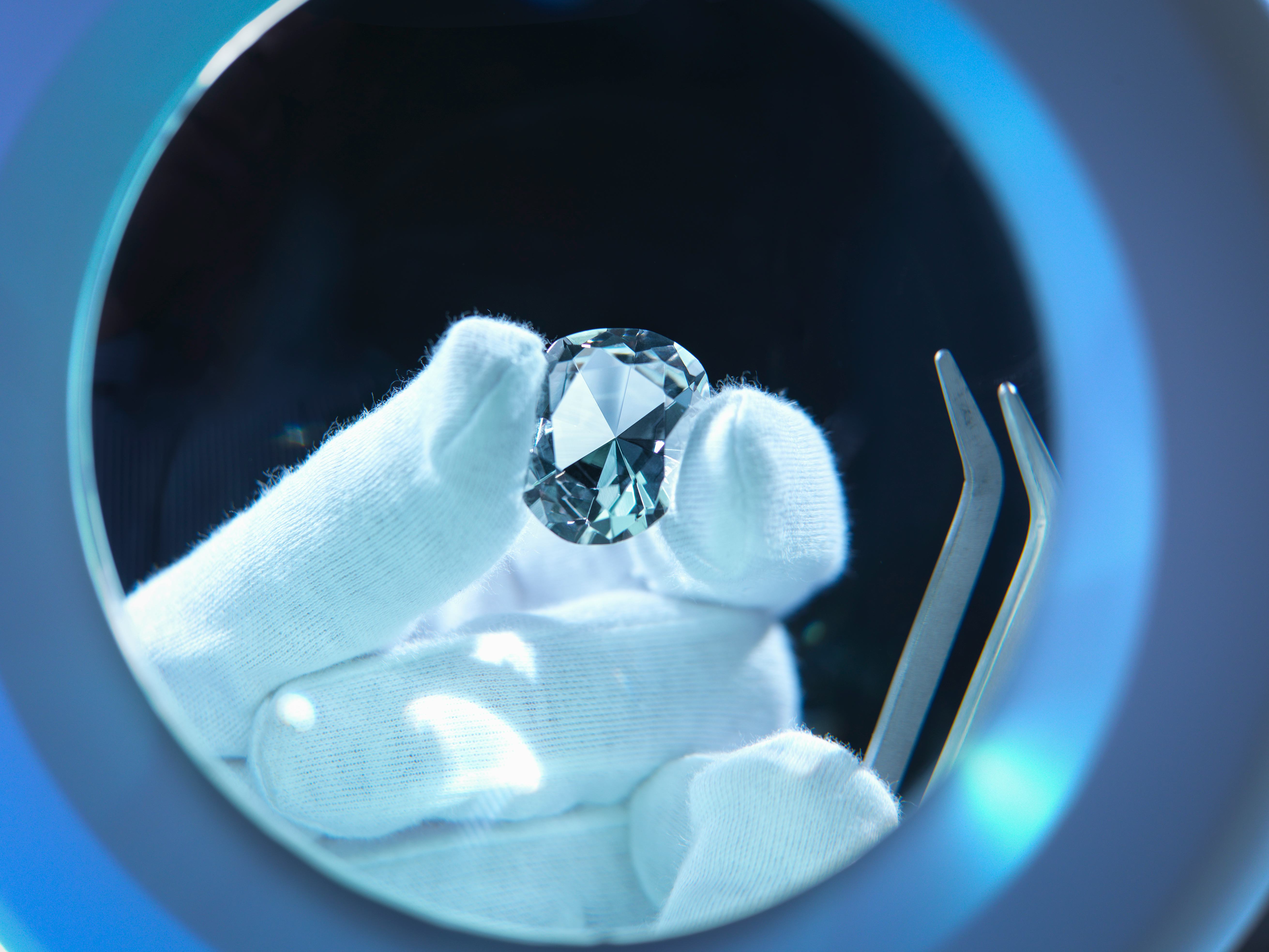 A close-up of a hand holding a lab-created diamond