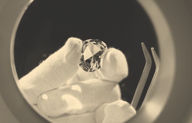 A close-up of a hand holding a lab-created diamond
