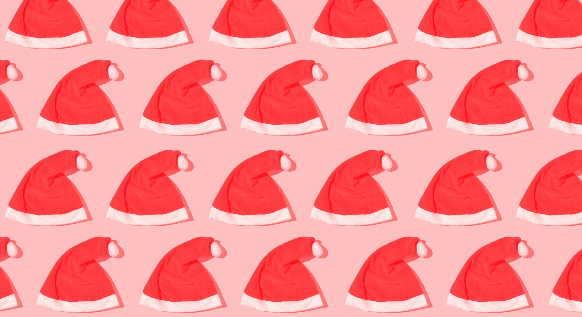 Santa Claus Christmas hats pattern with hard shadow on yellow background. Concept of gifts, celebrat...