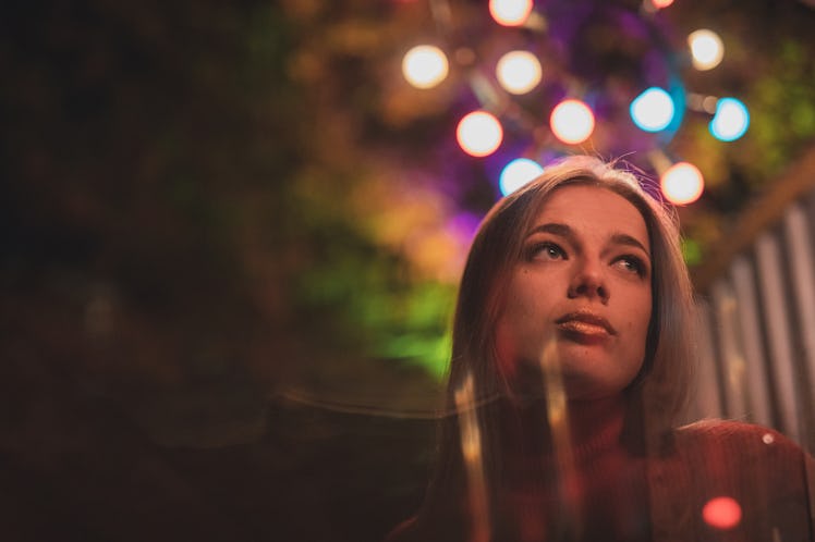 Young woman illuminated by neon lights, thinking about how the January 2022 full moon in Cancer will...