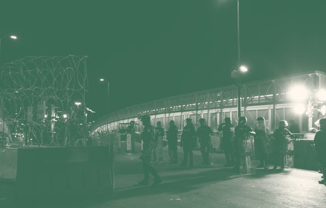 Customs and Border Protection officers dressed in riot gear stand guard atop the Paso del Norte Inte...