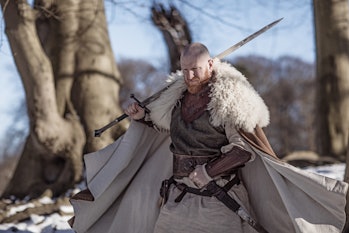 Handsome weapon wielding viking rus warrior outdoors in a snow filled wintry forest scene