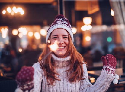 Young woman smiling and holding a sparkler during the week of December 27, 2021, which will be the b...