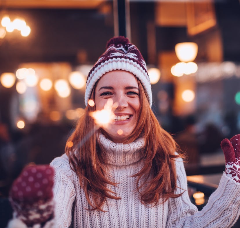 Young woman smiling and holding a sparkler during the week of December 27, 2021, which will be the b...