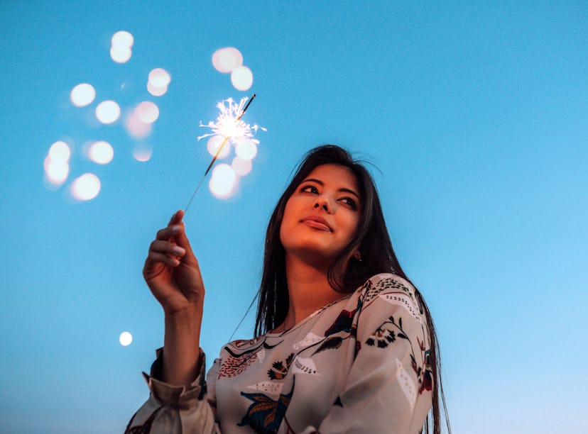 Young woman holding sparkler the week of December 27, 2021, which will be the worst for her unlucky ...