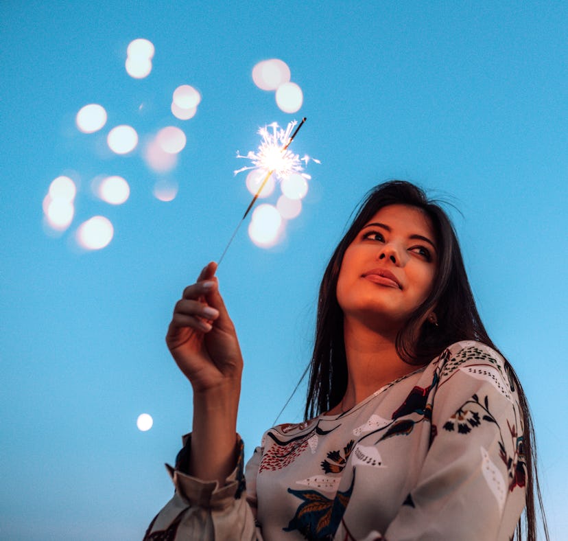 Young woman holding sparkler the week of December 27, 2021, which will be the worst for her unlucky ...