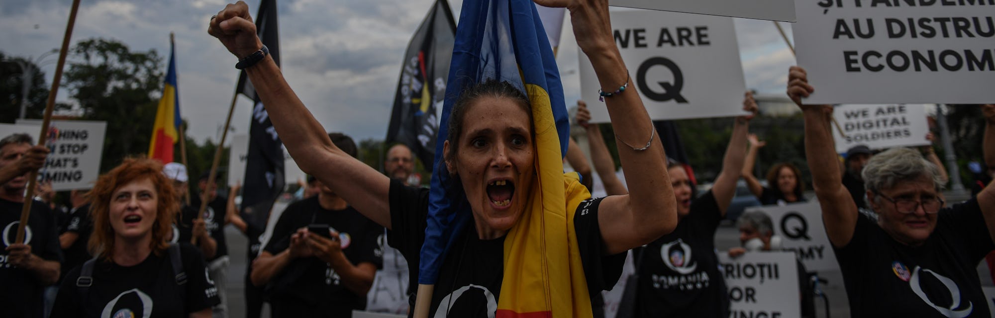 A woman shouts as she holds a placard reading "Q Army" (a reference to the Q-anon movement), during ...