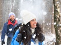 Happycouple with blue jacket having fun in the winter forest and using winter coat quotes as Instagr...