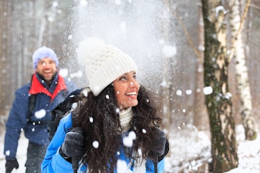 Happycouple with blue jacket having fun in the winter forest and using winter coat quotes as Instagr...