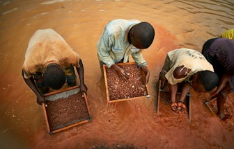 Miners sifting through the selected rich rock fragments in search of a diamond gem near an Angolan v...