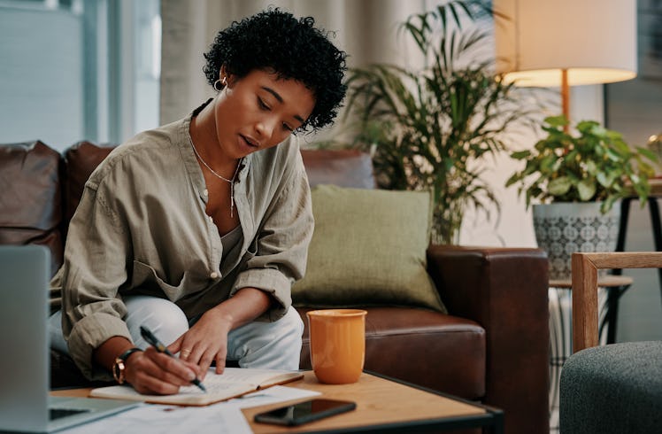 A young woman writing in her manifestation journal using manifestation prompts and templates.