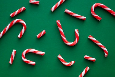 Candy cane crushed parts over emerald green background. Christmas greeting card.