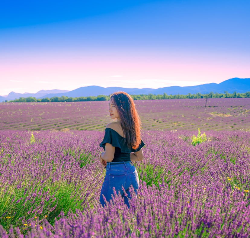 Woman enjoying lavender field as one of the very peri travel destinations inspired by Pantone's colo...