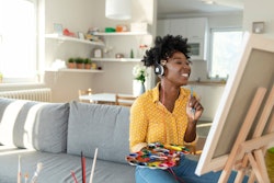 A woman paints in her living room. Here's your daily horoscope for December 22, 2021