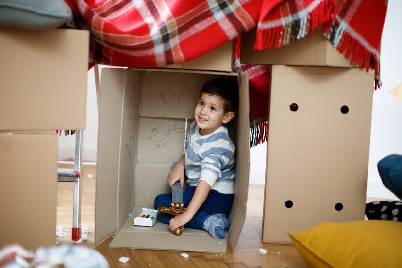 Smiling toddler sitting in turned cardboard box