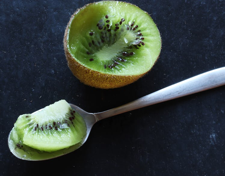 Photography of eaten kiwi and spoon on slate background for food illustration